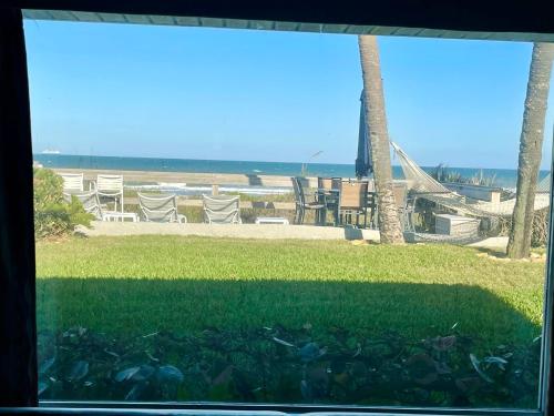 a window view of a beach with chairs and grass at Surf Studio Beach Resort in Cocoa Beach