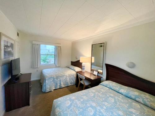 a hotel room with two beds and a desk with a mirror at Surf Studio Beach Resort in Cocoa Beach