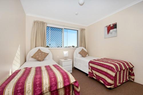 a hotel room with two beds and a desk at Blue Waters Apartments in Gold Coast