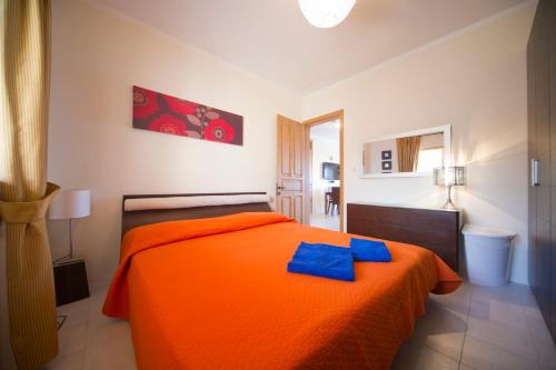 Un dormitorio con una cama naranja con toallas azules. en Ascot By The Sea, en St Paul's Bay
