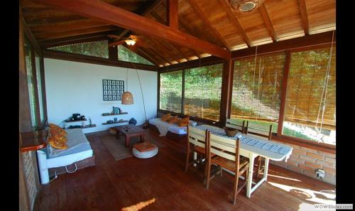 ein Wohnzimmer mit einem Tisch, Stühlen und Fenstern in der Unterkunft Casa Vista al Mar in Morro de São Paulo