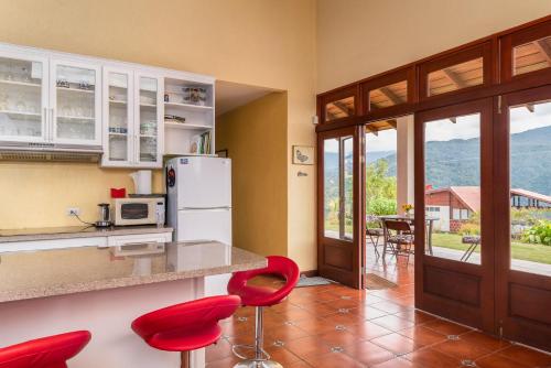 a kitchen with red chairs and a counter with a refrigerator at Casa Bartzis, Close to Orosi and Tapanti National Park in Orosí