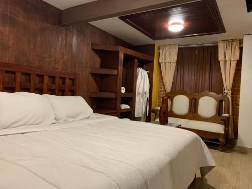 a bedroom with a large white bed and a chair at Quinta Maria Bonita Hotel Boutique in Xalapa