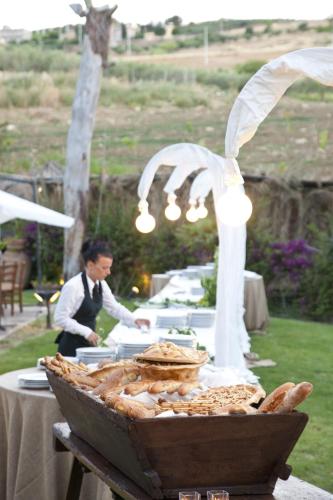 a table with a table with a woman preparing food at Agriturismo Baglio Fontana in Buseto Palizzolo