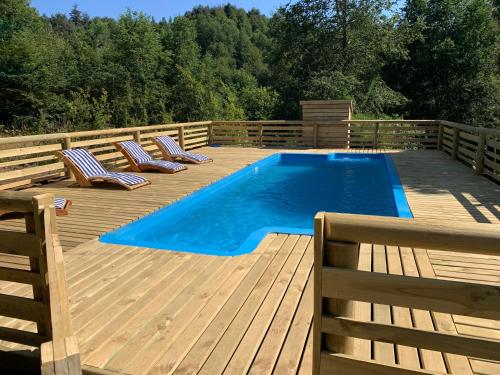 a swimming pool on a wooden deck with lounge chairs at Karkú Lodge in Pucón