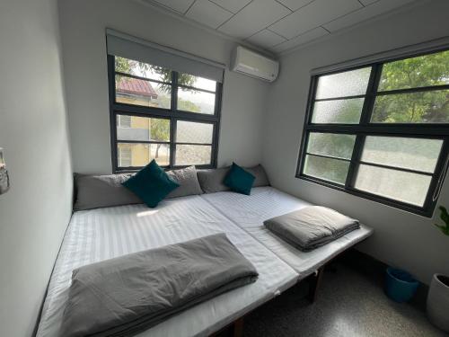 a small room with a bed and two windows at Little Garden Dream Life Home in Nantou City