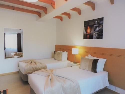 two beds in a room with white walls at Vila Barca in Madalena