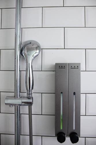 a shower head hanging on a white tiled wall at Little Garden Dream Life Home in Nantou City