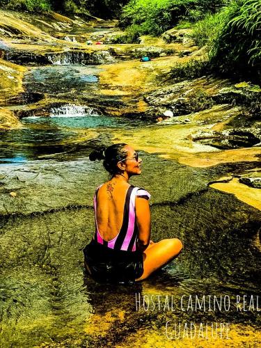 a woman sitting on the ground next to a river at Casa Hotel Camino Real in Guadalupe