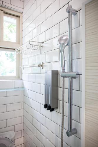 a white tiled bathroom with a blow dryer on the wall at Little Garden Dream Life Home in Nantou City