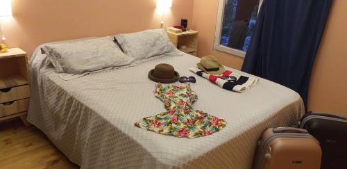 a bed with two hats and a dress on it at Angelina's House by L&L in Mar del Plata