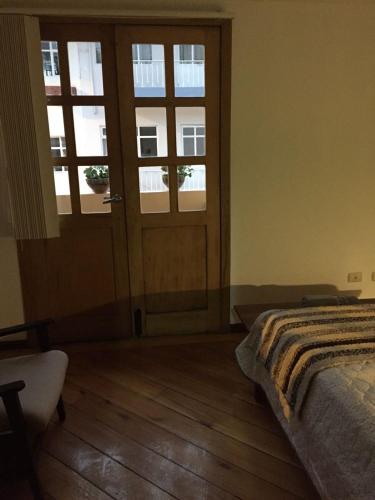 a bedroom with a bed and a door with windows at Ñañas Hostel in Cuenca