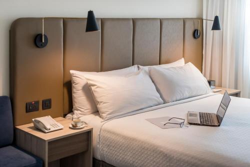 a bedroom with a bed with a laptop and a table at Crowne Plaza Lima by IHG in Lima