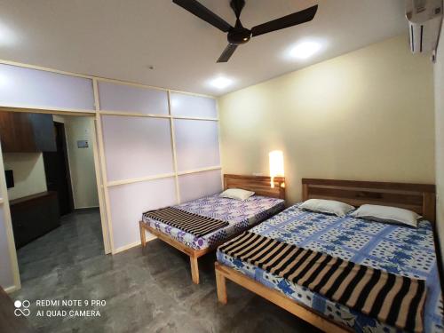 a bedroom with two beds and a ceiling fan at Godwill Kimo Guest house Seraulim in Madgaon