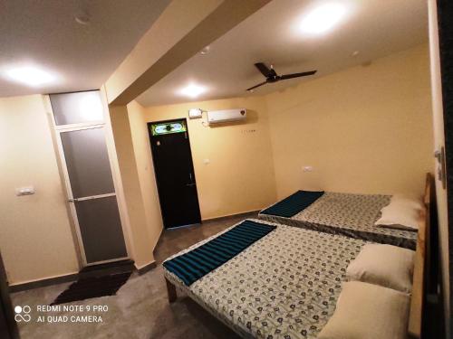 a small room with two beds and a door at Godwill Kimo Guest house Seraulim in Madgaon