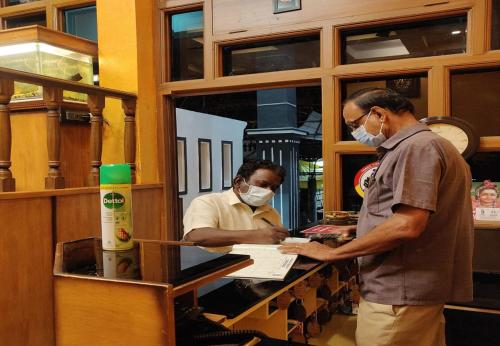 two men wearing face masks at a cash register at Arudhra Residency in Chidambaram