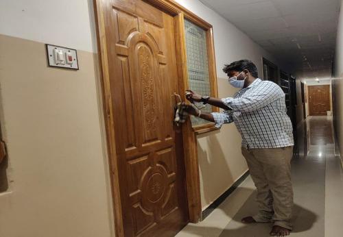 a man wearing a mask opening a door at Arudhra Residency in Chidambaram