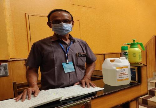 a man wearing a mask standing at a desk with a keyboard at Arudhra Residency in Chidambaram