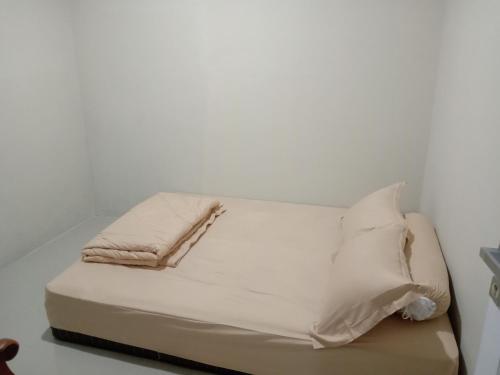 een bed met witte lakens en kussens erop bij Guesthouse - Biru Homestay in Tjilimus