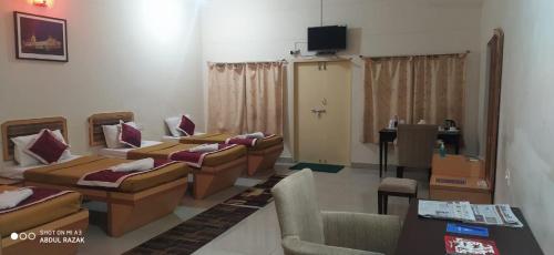a room with a bunch of beds and a table at KSTDC Mayura Durg Chitradurga in Chitradurga