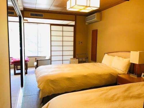 a hotel room with two beds and a window at Tateshina Grand Hotel Takinoyu in Chino