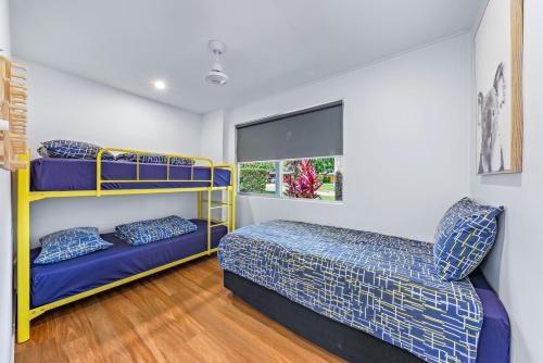 a bedroom with two bunk beds and a window at BIG4 Whitsundays Tropical Eco Resort in Airlie Beach