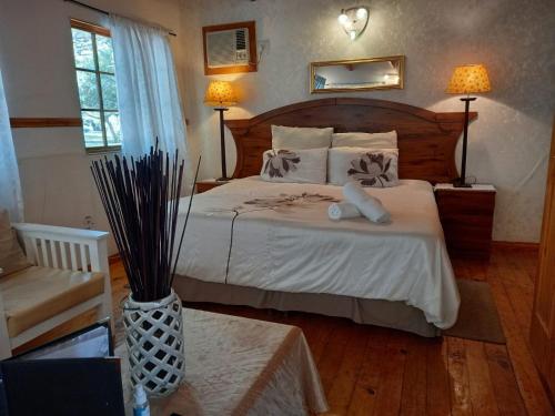 1 dormitorio con 1 cama grande con sábanas blancas en Acacia Bush Lodge en Pietermaritzburg