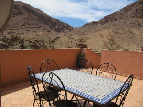 una mesa y sillas en un balcón con montañas en Auberge Cavaliers, en Aït Baha