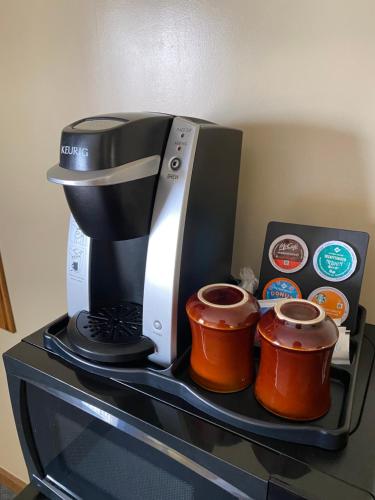 Thunderbird Lodge, Norman, OK في نورمان: آلة صنع القهوة وكوبين على منضدة