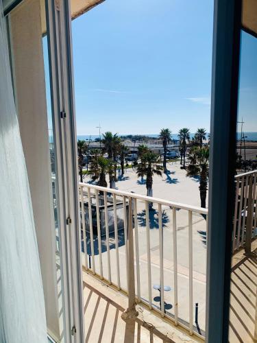 a balcony with a view of the beach and palm trees at Face a la mer Fleury in Fleury