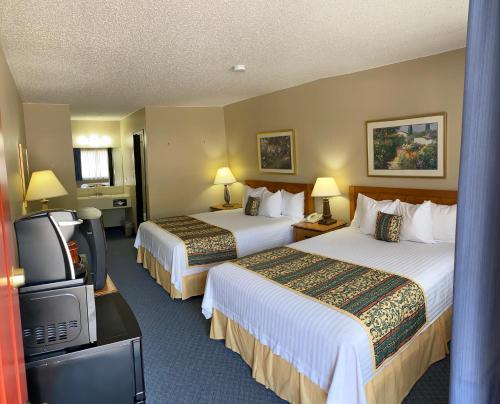 um quarto de hotel com duas camas e uma televisão de ecrã plano em Thunderbird Lodge, Norman, OK em Norman