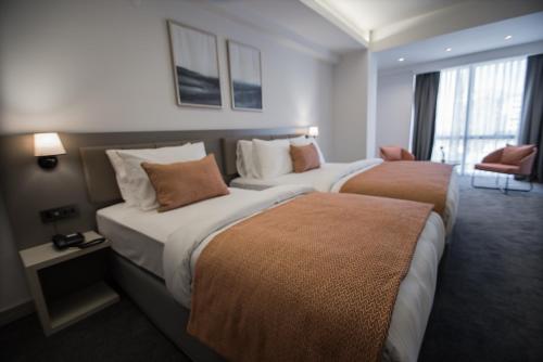 a hotel room with two beds and a chair at Dovv Hotel Busıness in Gaziemir
