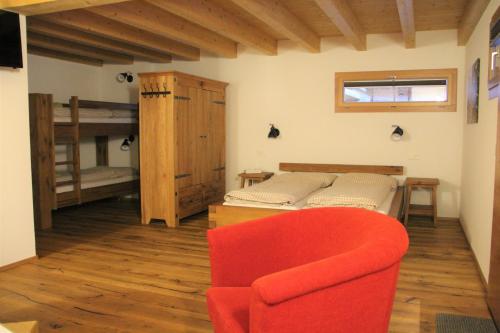 a living room with a bed and a red chair at B&B Hängebrigga in Ernen
