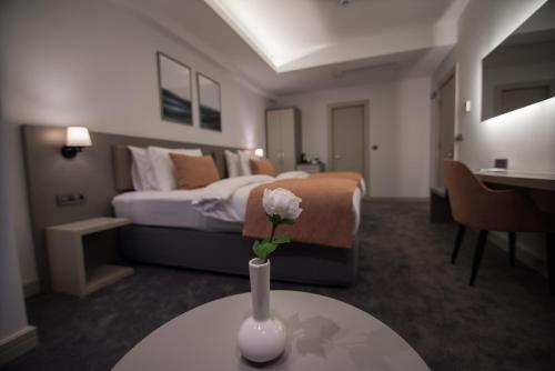 a room with a bed and a vase with a flower on a table at Dovv Hotel Busıness in Gaziemir