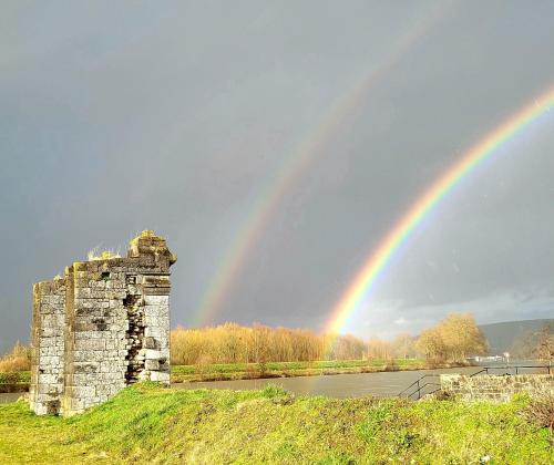 a rainbow over an old building and a tower at Le Soleil Couchant/Chambre d'hôtes in Givet