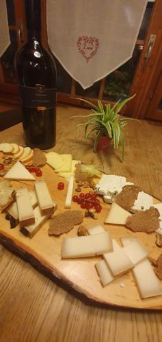 a wooden cutting board with cheese and a bottle of wine at Hôtel Dents de Veisivi in Haudères