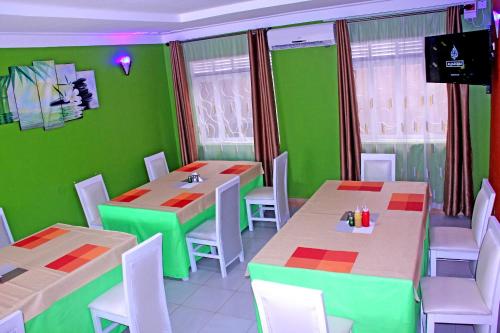 a restaurant with green walls and white tables and chairs at Bethel Resort & Hotels in Gulu