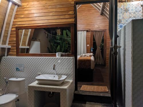 uma casa de banho com um lavatório, um WC e um espelho. em Paradesa Villa em Gili Trawangan
