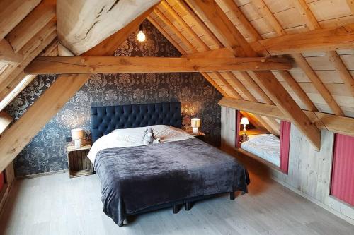 ein Schlafzimmer mit einem blauen Bett im Dachgeschoss in der Unterkunft Belle Vie Comfortable guest house near Bruges in Oostkamp