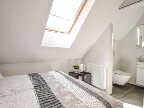 a white bedroom with a bed and a bathroom at Apartamenty Ostoja in Łeba