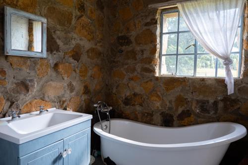 a bathroom with a tub and a sink and a window at Kliphuis in Van Reenen