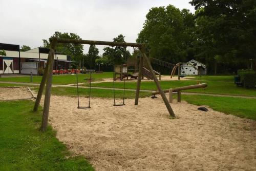 a park with a swing set in the sand at Chalet Bergen NH, Schoorl, Schoorldam in Warmenhuizen