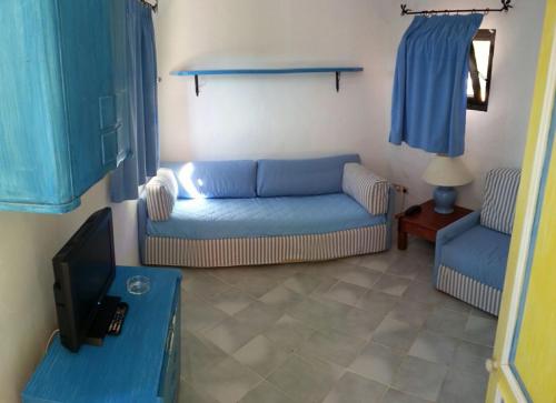 a living room with a blue couch and a tv at NRH Baja Sardinia Cottage in Baja Sardinia