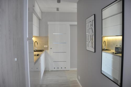 a white kitchen with white cabinets and a hallway at Penelopa Silver in Świnoujście