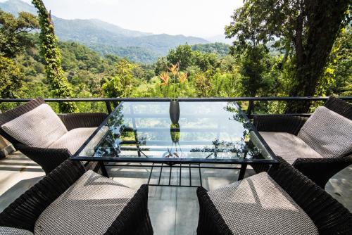 a glass balcony with chairs and a view of the mountains at Ella Planters Bungalow in Ella