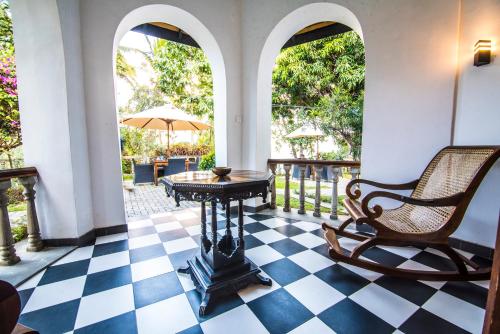a room with a chair and a table on a checkered floor at Ella Planters Bungalow in Ella