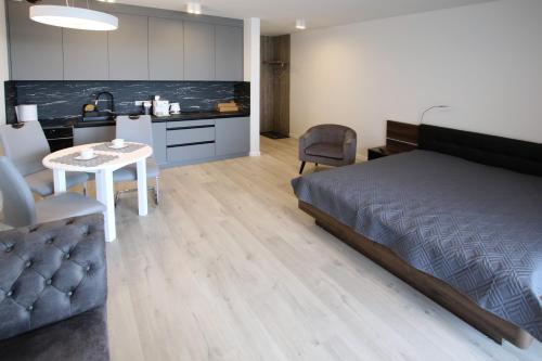 a bedroom with a bed and a table and a kitchen at LUX Apartament Rogowo Pearl in Rogowo