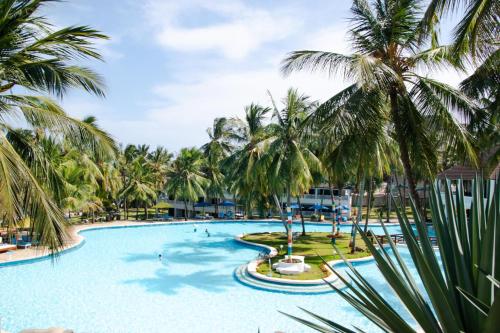 a pool with palm trees and people in it at PrideInn Flamingo Beach Resort & Spa Mombasa in Mombasa