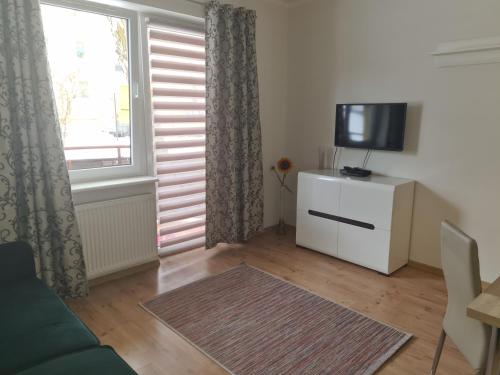 a living room with a couch and a tv and a window at Apartament z garażem podziemnym - Augustowska in Olsztyn