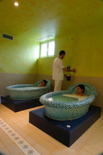 a man standing in a bathroom with two large tubs at Silken Spa La Hacienda De Don Juan in Llanes